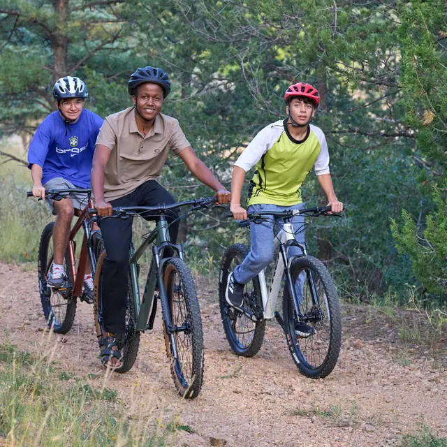 Three students mountain biking on a forest trail
