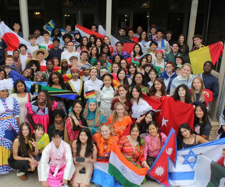 A large group of UWC-USA students in traditional dress, holding the flags of their home countries