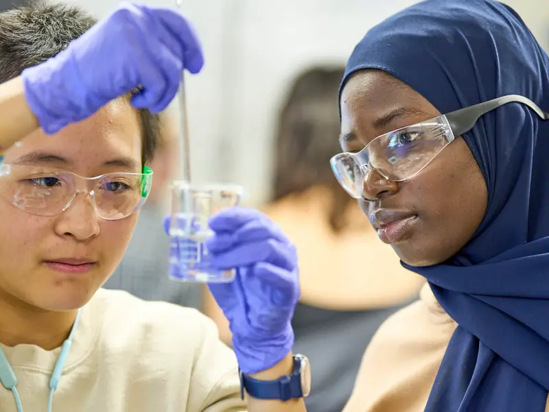 Two students in safety glasses doing a chemistry experiment