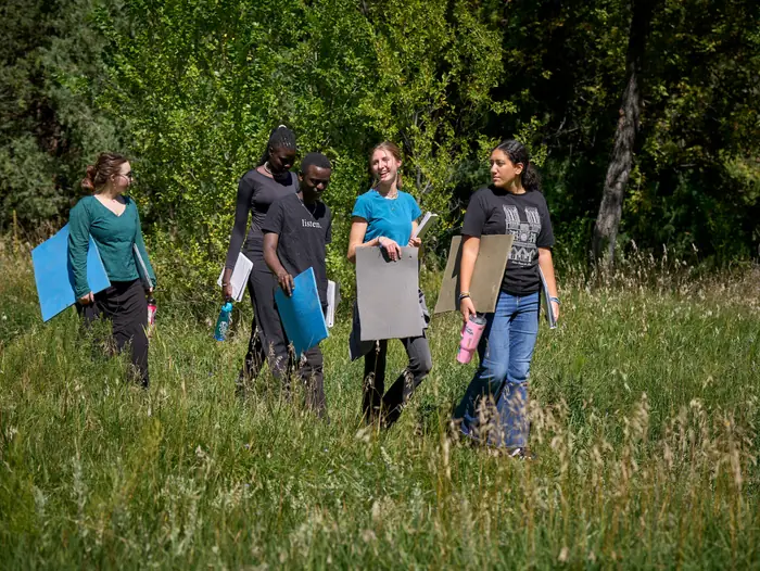 Students with notebooks walking through a meadow for a field class