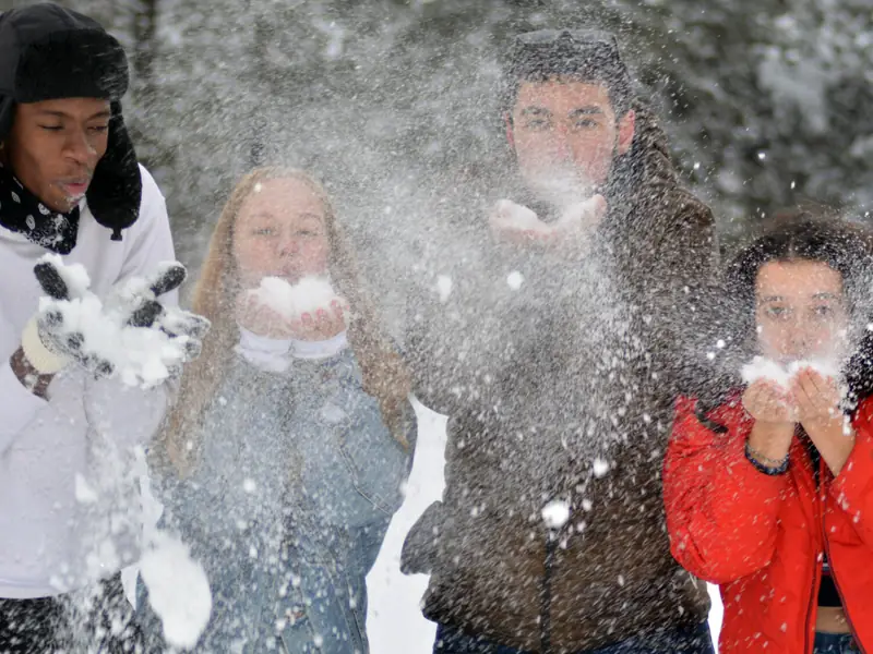 Students blowing snow from their hands on a winter day on campus