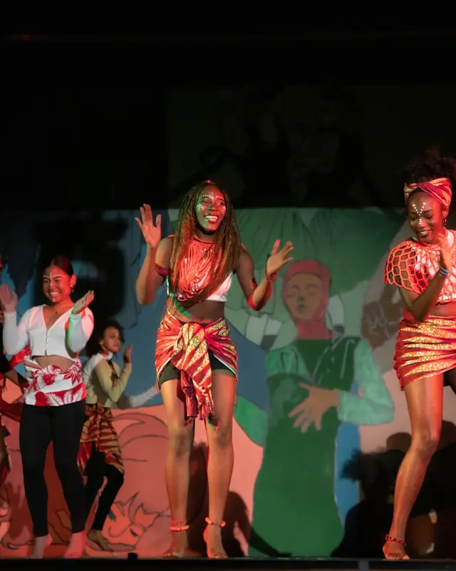Students dancing on stage in colourful costumes at a cultural show